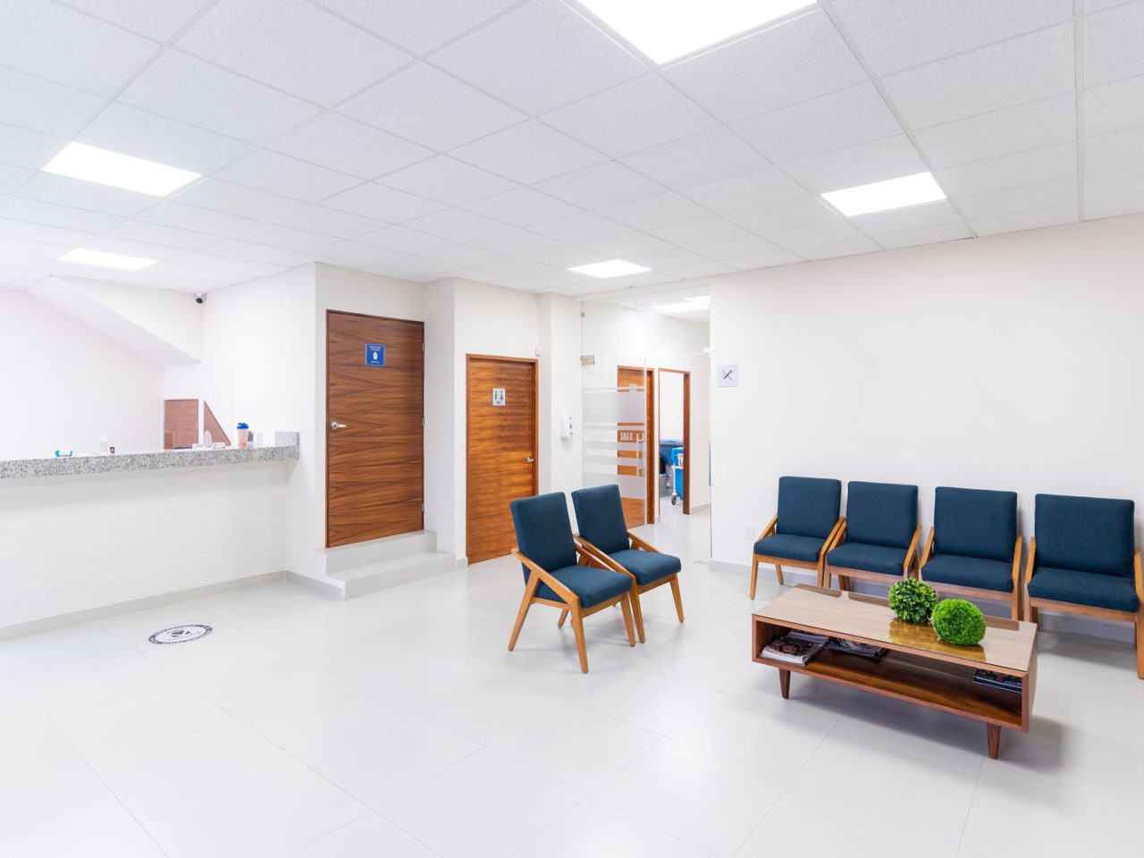 A bright, empty clinic waiting area with a reception counter and seating.