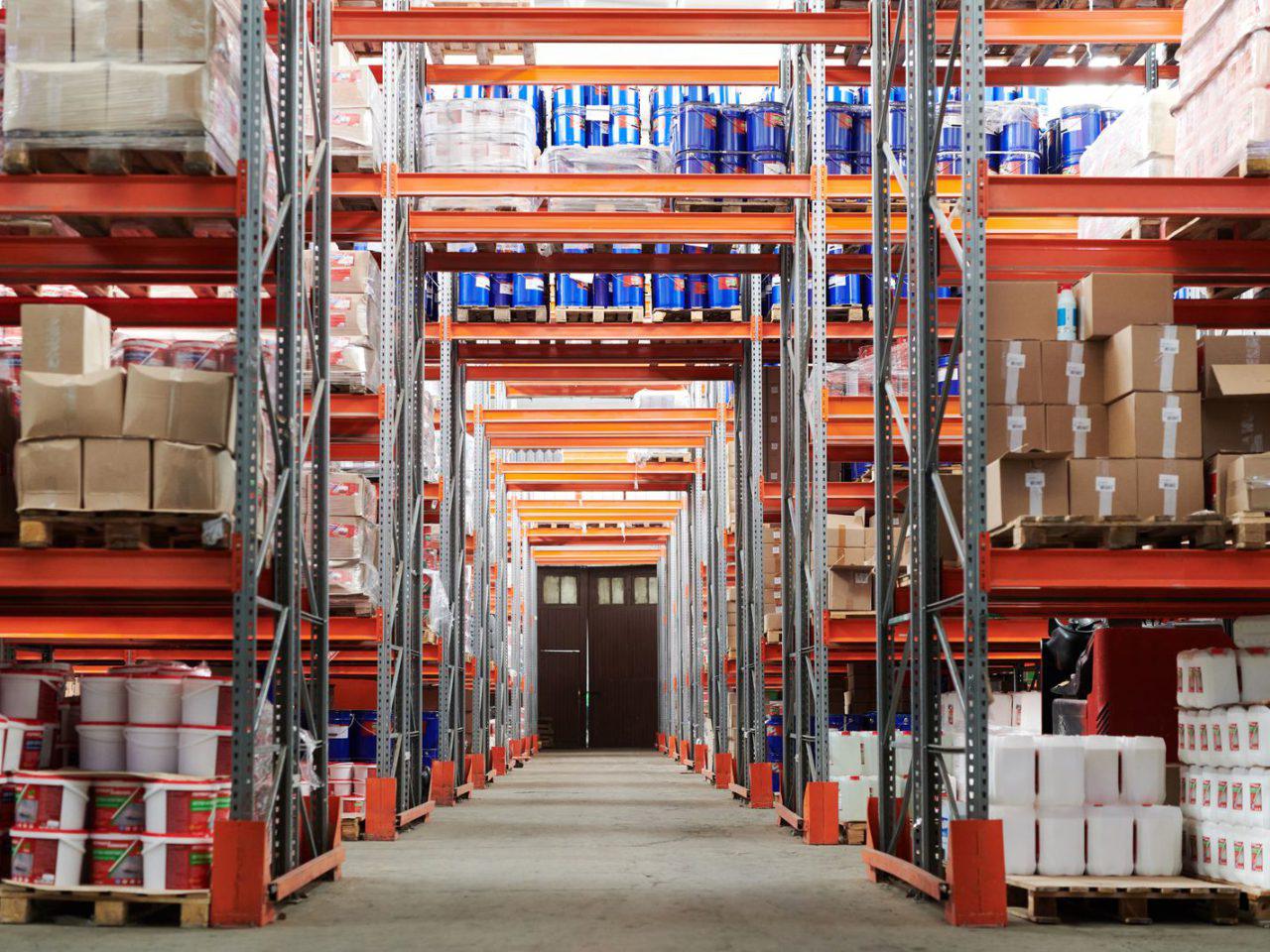 An aisle of stacked pallet racking inside a warehouse and distribution facility.